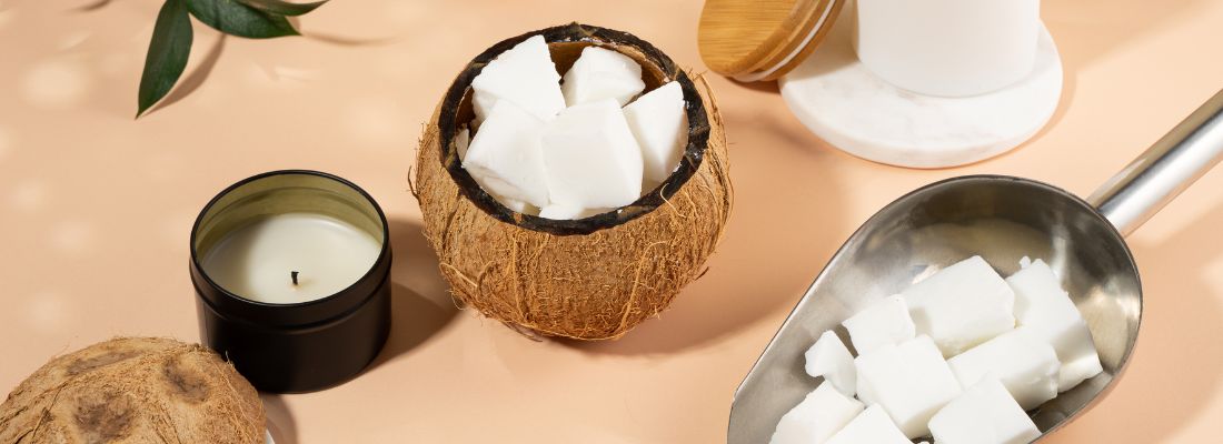 Noix de coco remplie de cire végétale à côté d'une bougie de soja